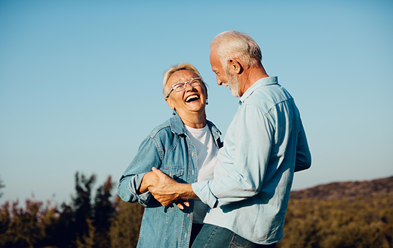 Couple laughing in front of a cloudless sky