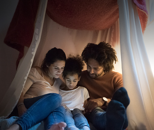 man, woman and child snuggled together under a makeshift tent