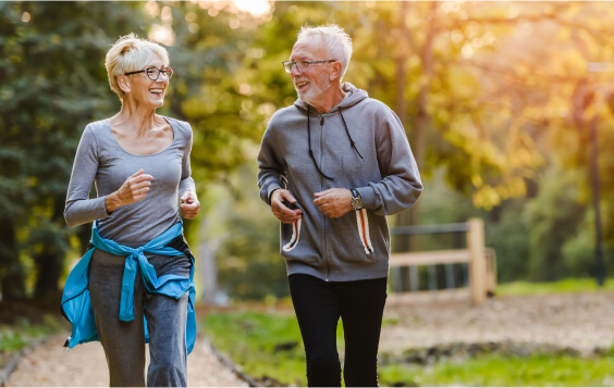 Older couple jogging through a park