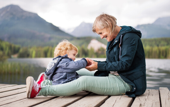 Grandmother and grandchild sitting on a deck over a lake