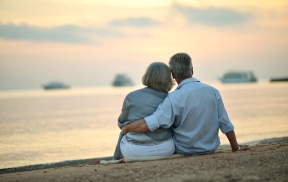 Older couple sitting on the beach watching the sunset