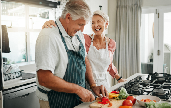 Older couple laughing while cooking