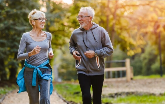 Older couple jogging through a park