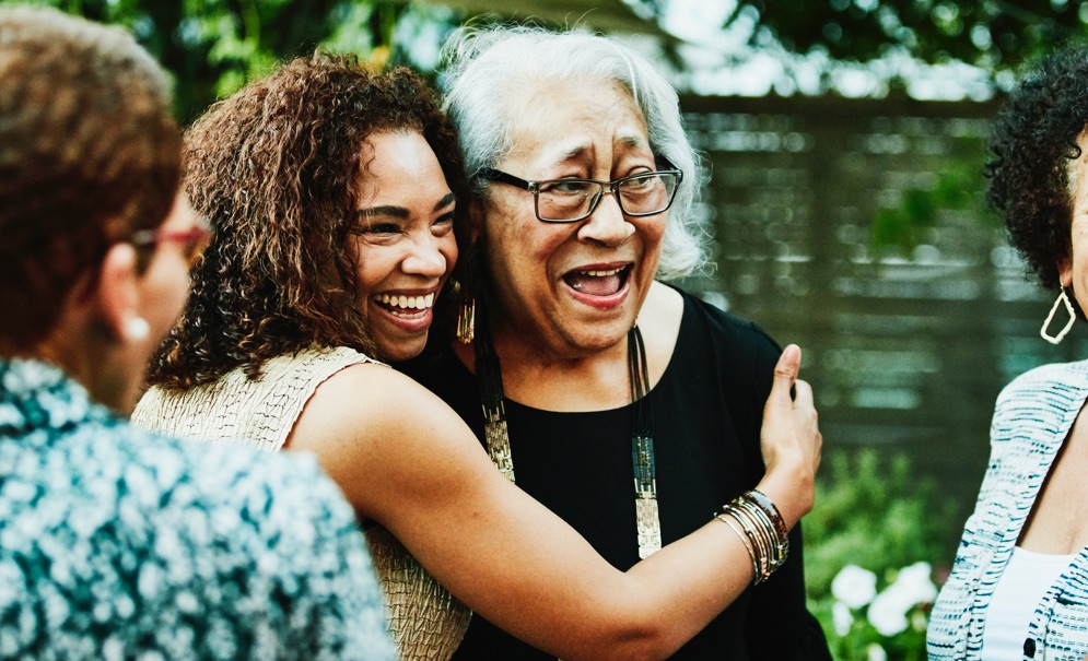 Smiling woman hugs elderly woman.
