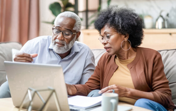 Older man and woman looking at laptop in their home