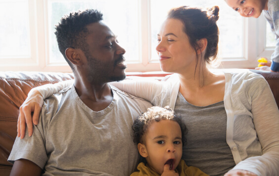 Affectionate multi-ethnic young family on living room sofa
