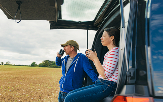 A couple having a cup of tea by their camper van