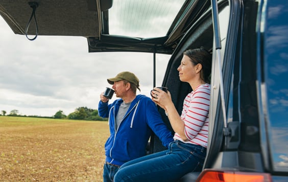 A couple having a cup of tea by their camper van