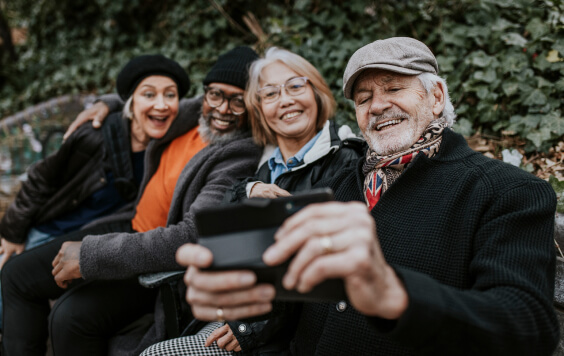 Senior friends taking selfie at a park bench