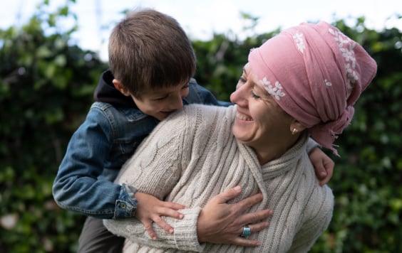 Woman with a head wrap smiling whilst a giving a young boy a piggyback