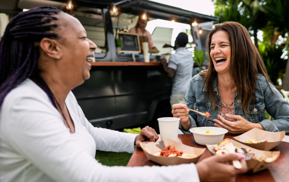 Two women laughing and eating outside