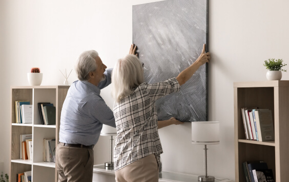 Older couple hanging up a painting