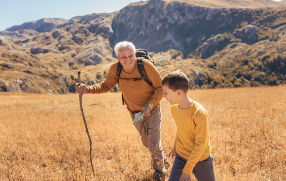 Senior man with grandson on country walk in autumn