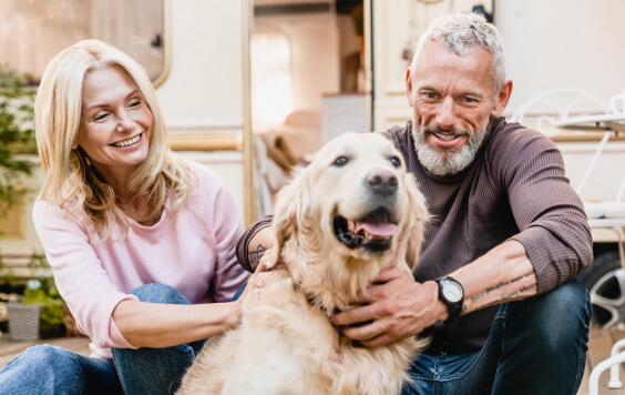 50s beautiful married couple spending time with their dog outside camper van