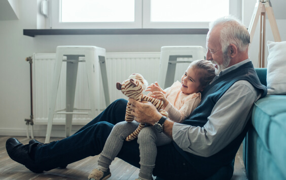 Grandfather and granddaughter sat on the floor playing with a cuddly toy