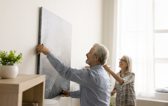 Older couple hanging up a painting
