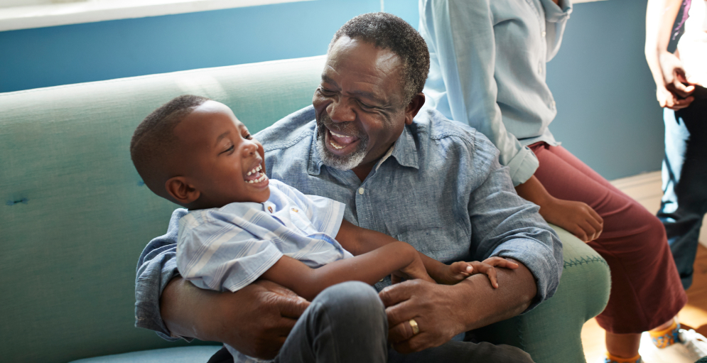 High angle view of happy man playing with boy while sitting on sofa at home
