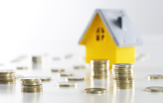 yellow model house with a grey roof with coins piled up next to it