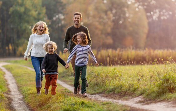 Young family walking down a dirt path at sunset