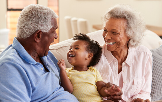 Two grandparents laughing with their grandchild