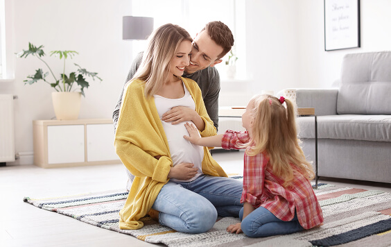 Pregnant woman with her partner and daughter on the floor