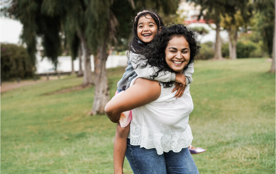 Happy Mother giving young, laughing daughter a piggyback