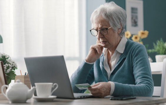 Confused senior woman using her credit card online 