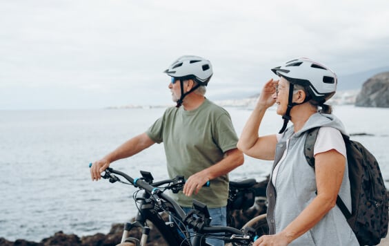Two happy old mature people enjoying and riding bikes together to be fit and healthy outdoors