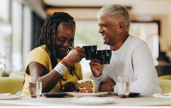 Older couple smiling whilst drinking from a mug